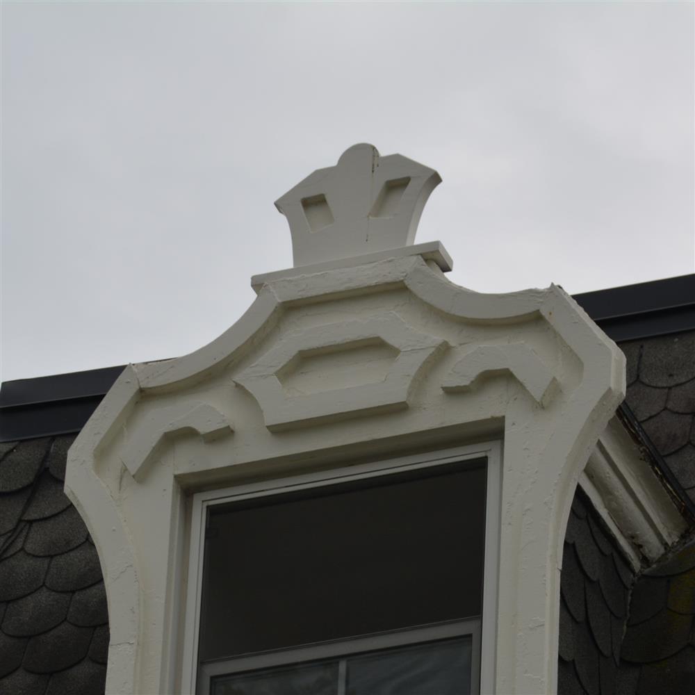 Elaborate geometric shape of carved and cut wood around a window, high on a building
